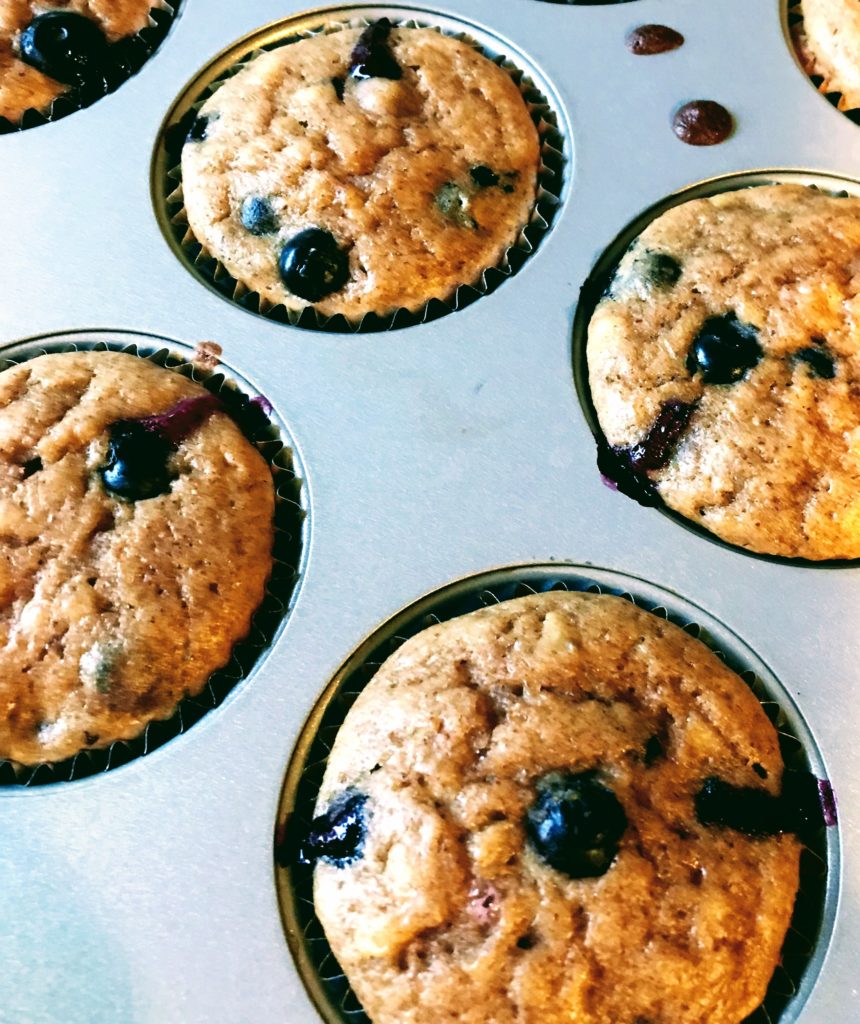 Four blueberry muffins in a muffin tin.